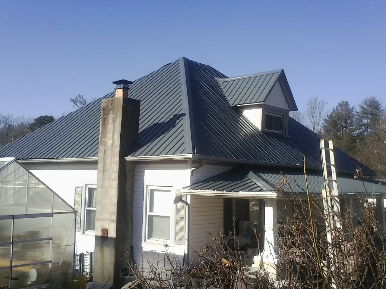 Dark blue standing seam metal roof on a white farmhouse with dormer — Slate & Tile Roof Repair by Roofing Brothers in Pamplico