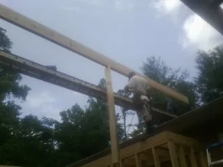 Carpenter setting a ridge beam over a new addition frame — Ice Dam Removal by Roofing Brothers in Pamplico