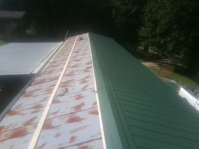 Old rusted panels beside newly installed green metal roofing — Wind Damage Roof Repair by Roofing Brothers in Pamplico