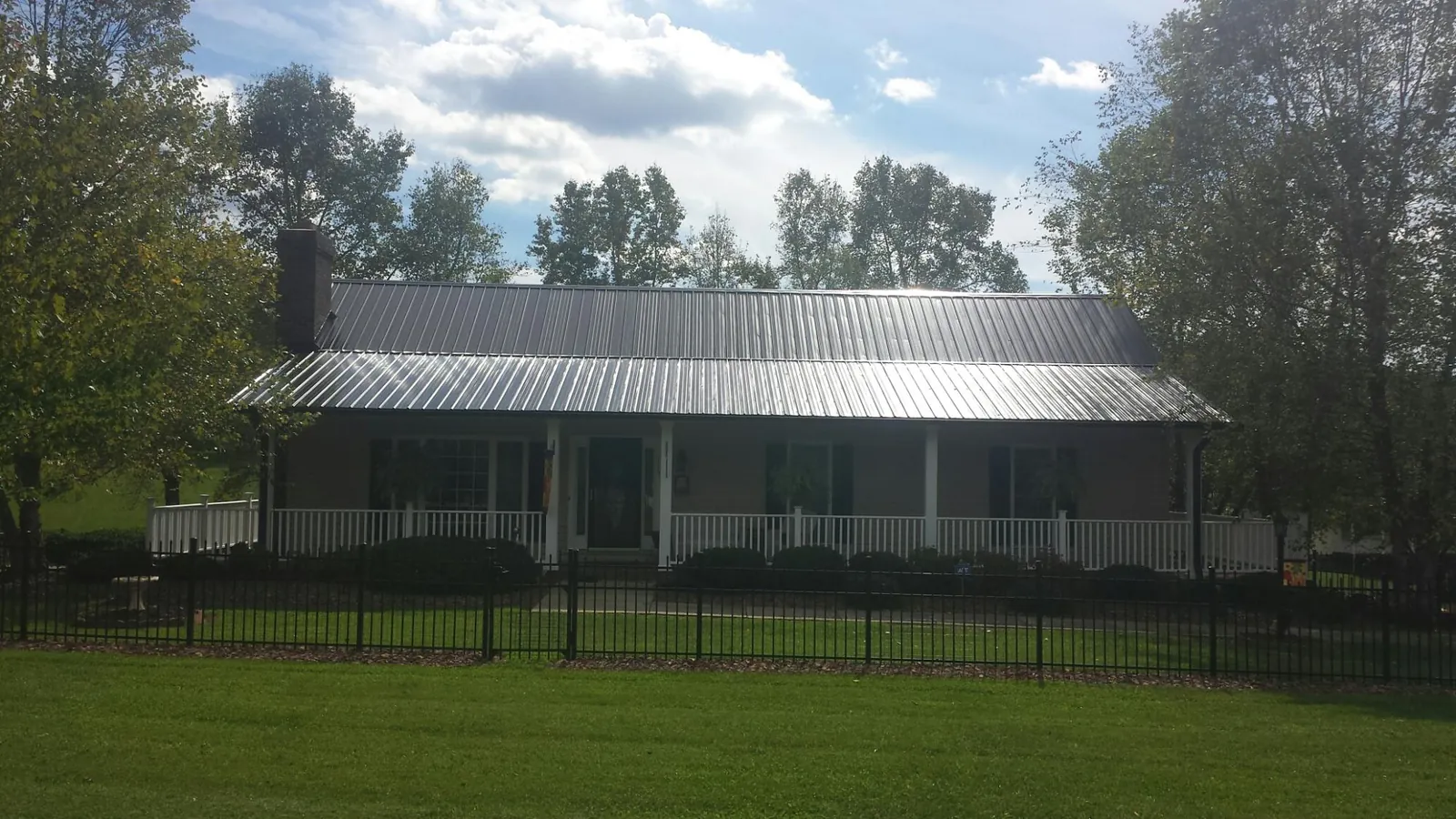 Gray metal roof on a brick ranch with a full width front porch — Gutter Guard Installation work by our crew in Pamplico