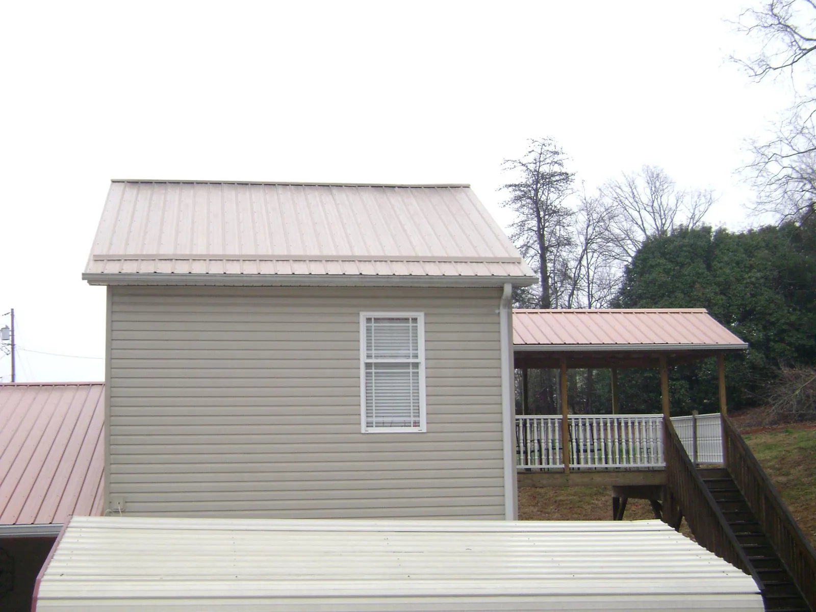Tan metal roofs on a two story addition and attached porch, from a Roof Replacement job in Pamplico