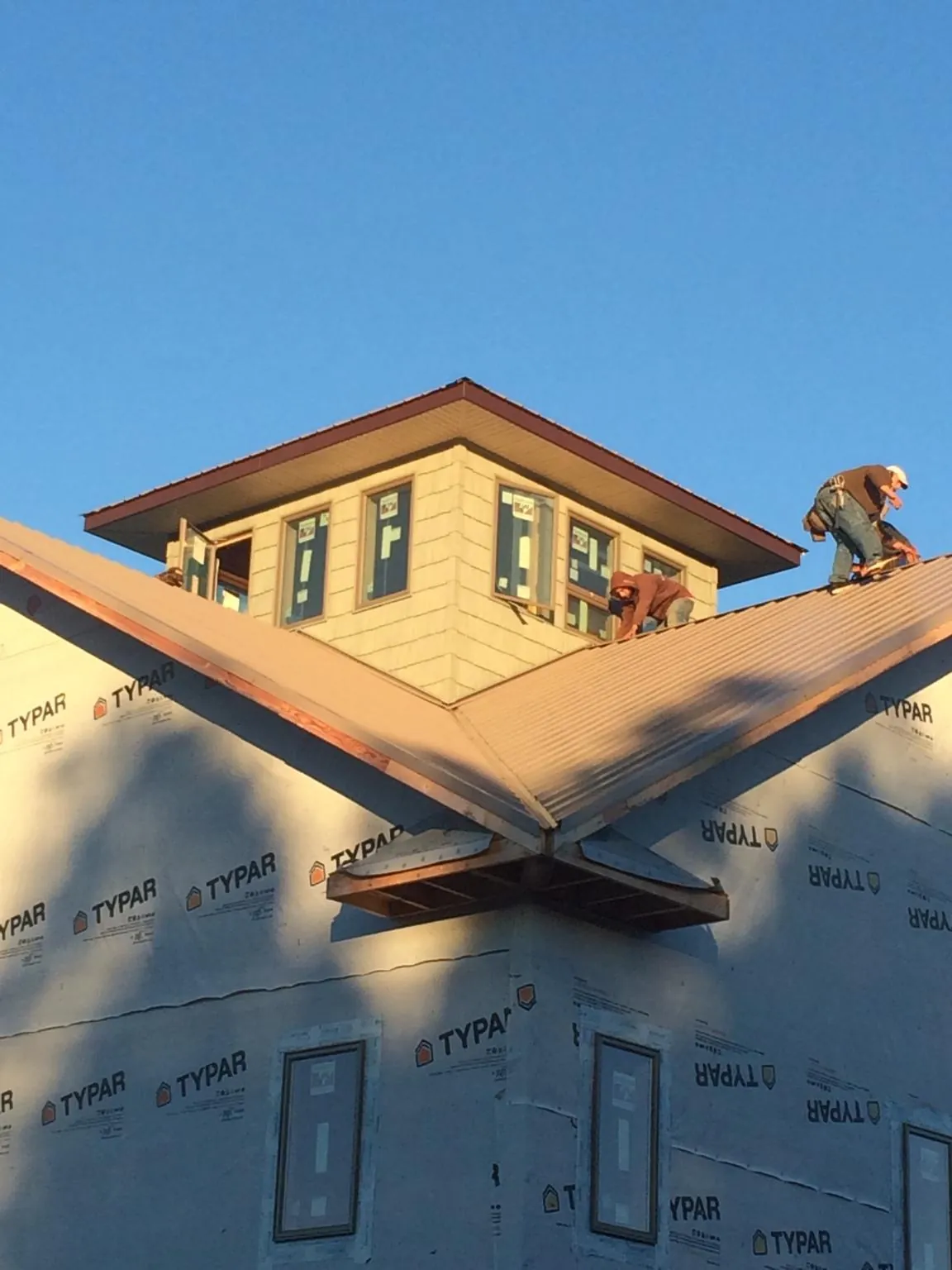 Roofers working around a rooftop cupola on a new metal roof at sunset — Roof Waterproofing in Pamplico by Roofing Brothers